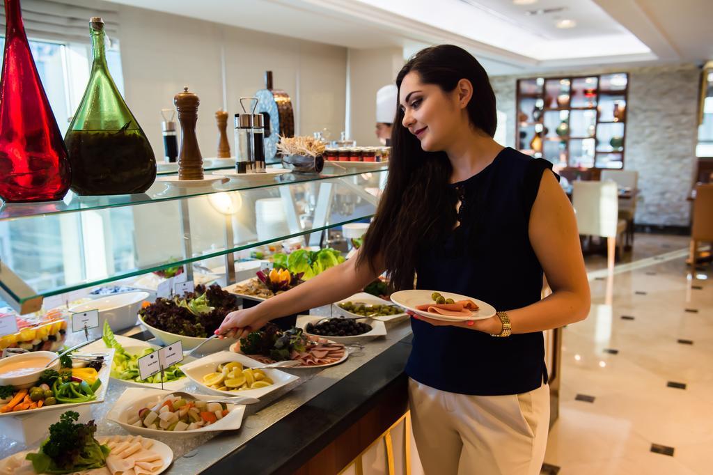 Grand Mercure Majlis Residences Абу Даби Екстериор снимка A woman selecting food from a buffet